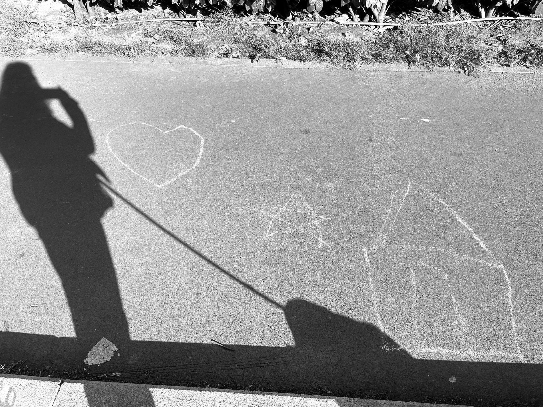 12 maggio 2022. Autoritratto con cane e disegno di bambino/a in gesso. Rappresenta una casa, una stella e un cuore, nei giardini di Via Benedetto Marcello a Milano.