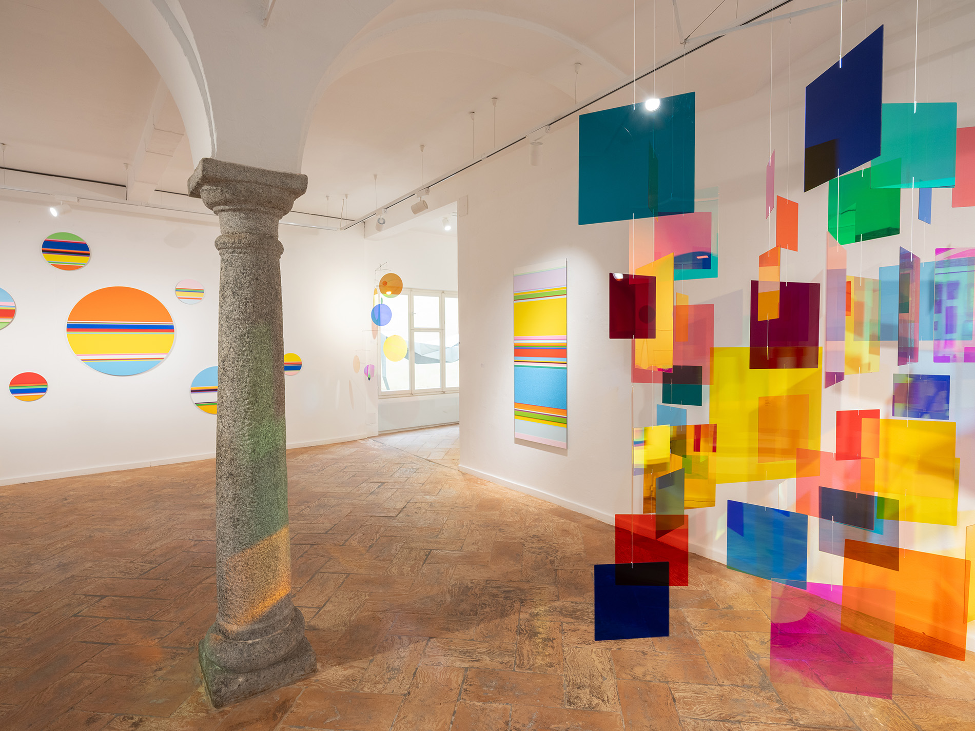 Ausstellungsansicht: links Nicholas Bodde, No. 1764, 1750, 1747, 1688, 1759, 1748, 1761, 1664 Circle, 2024-2026, diverse Grössen; No. 1699 Vertical, 2025, alle Öl und Acryl auf Aluminium; rechts Rosali Schweizer, Diversity, 2022, Acrylglas und Metallrahmen, 200 x 200 cm. Foto: Alfio Tommasini